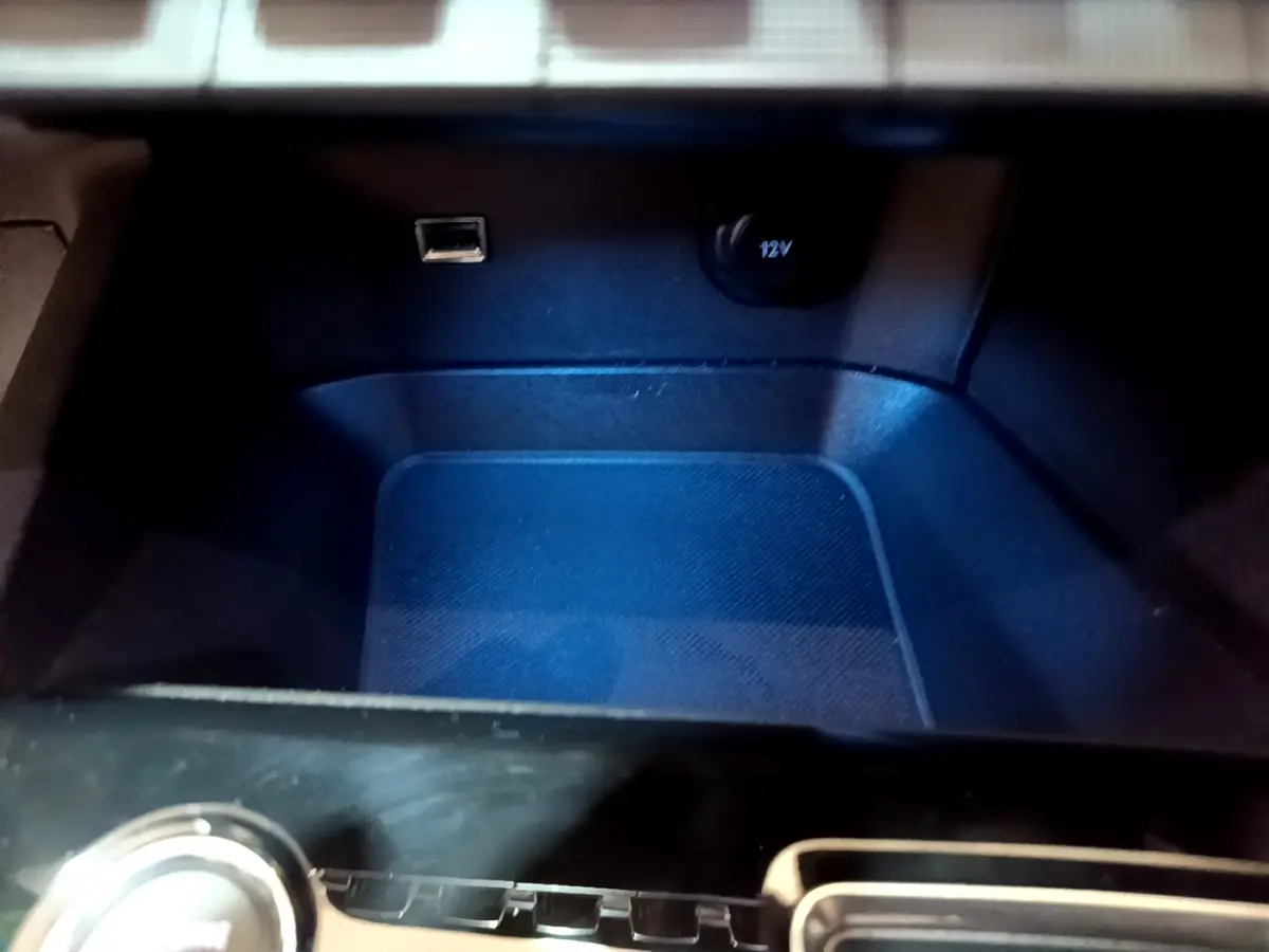 Gros plan sur la prise USB et la prise 12V dans le rangement central du Peugeot 3008 noir 2023.