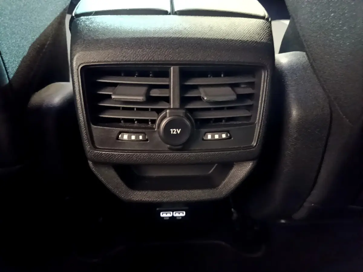 Détail de la console arrière noire du Peugeot 3008 2023 avec prises 12V et USB visibles.