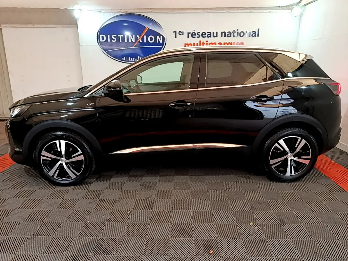 Profil droit d’un Peugeot 3008 GT noir 2023 avec jantes alliage et vitres teintées en intérieur showroom.