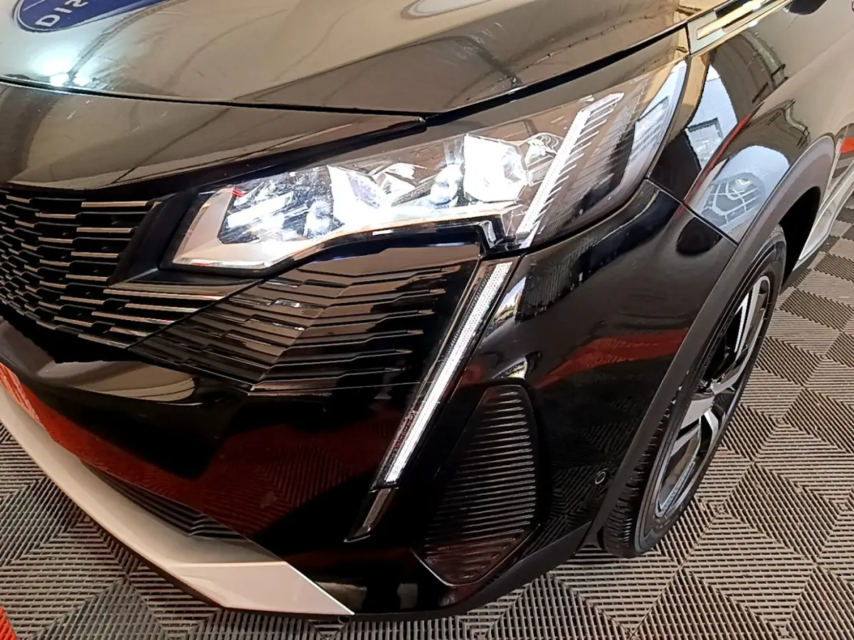 Gros plan sur l'avant droit noir brillant du Peugeot 3008 2023, mettant en valeur son phare LED et sa calandre distinctive.