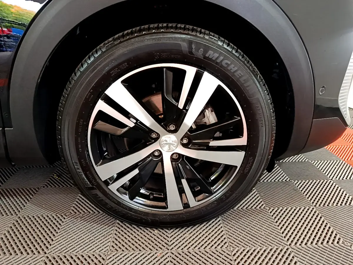Gros plan sur la roue avant droite noire du Peugeot 3008 2023 avec jante alliage bicolore et pneu Michelin.