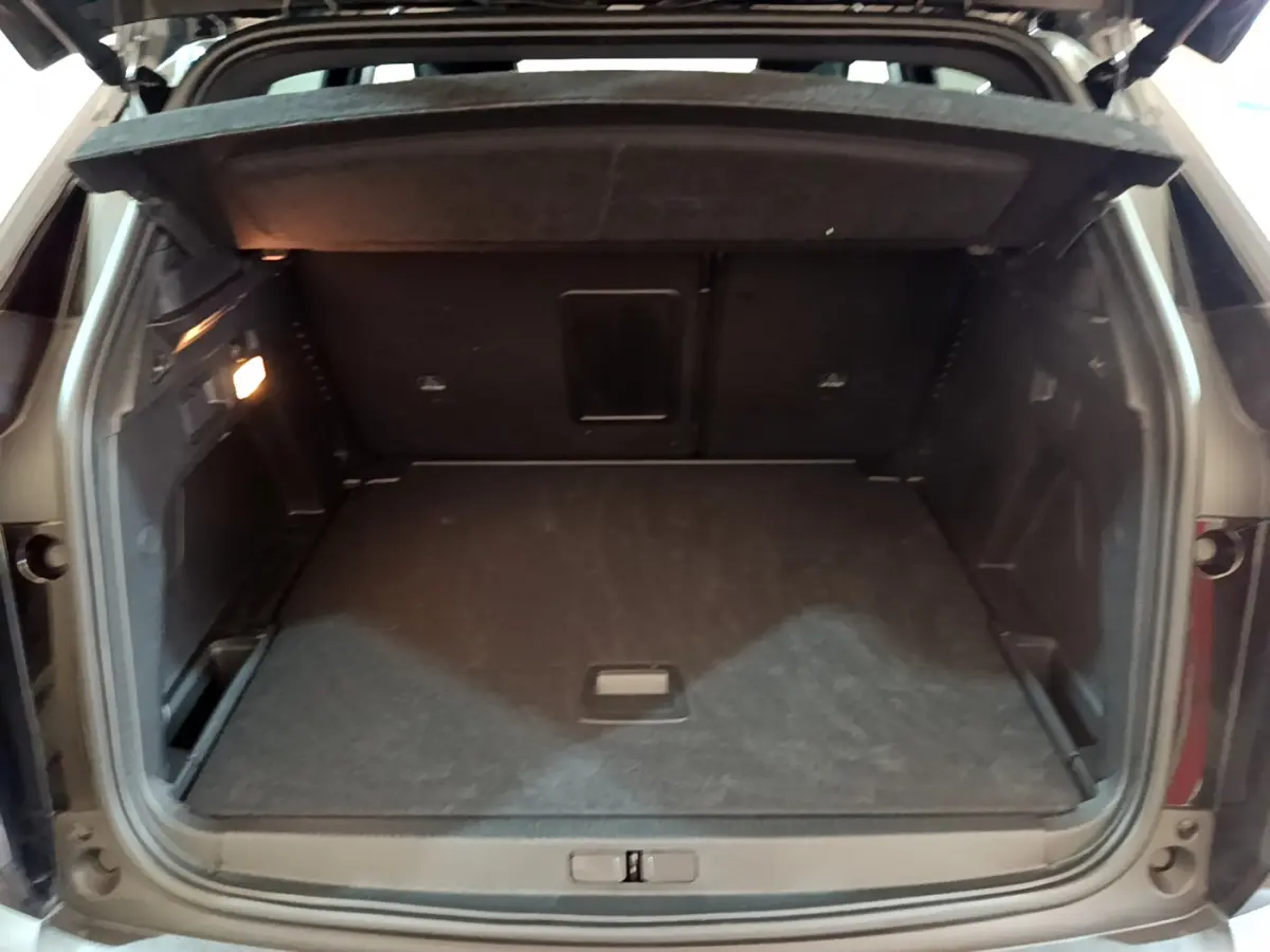 Coffre ouvert vu de l'arrière du Peugeot 3008 noir, montrant un espace de chargement spacieux et un éclairage intérieur.