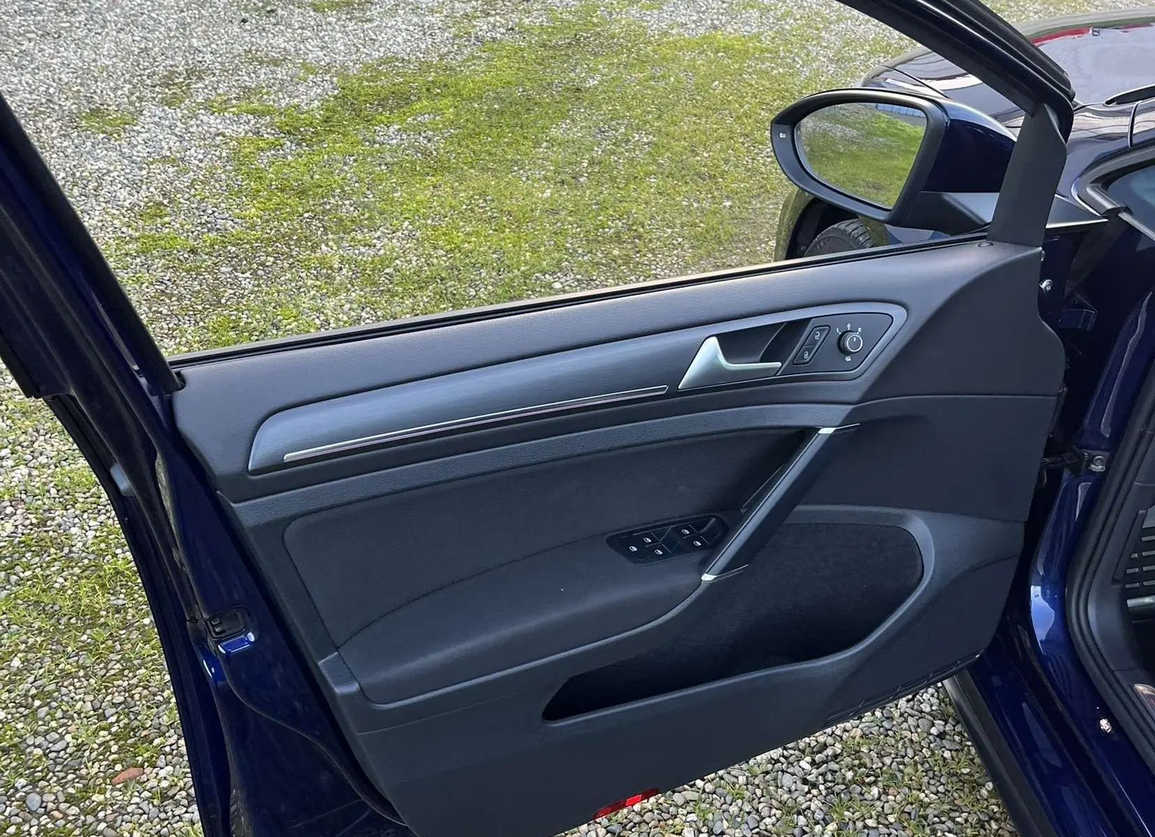 Porte avant gauche ouverte d'une Volkswagen Golf VII GTI Performance bleu lapiz, montrant les commandes de vitre et le miroir extérieur.