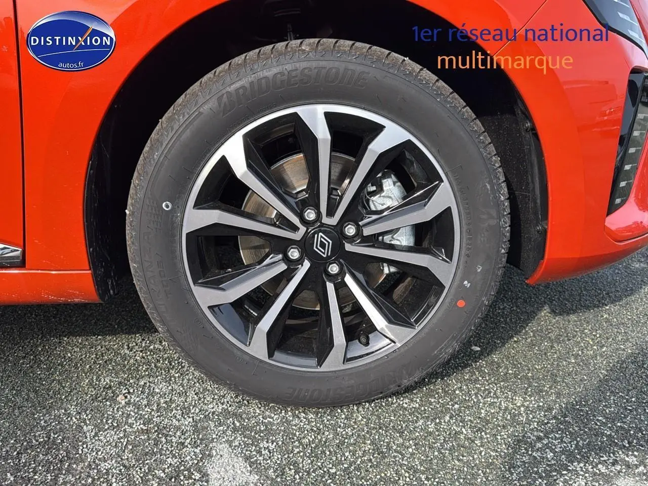 Gros plan sur la jante alu noire et grise du côté avant droit d'une Renault Clio V orange Valencia.