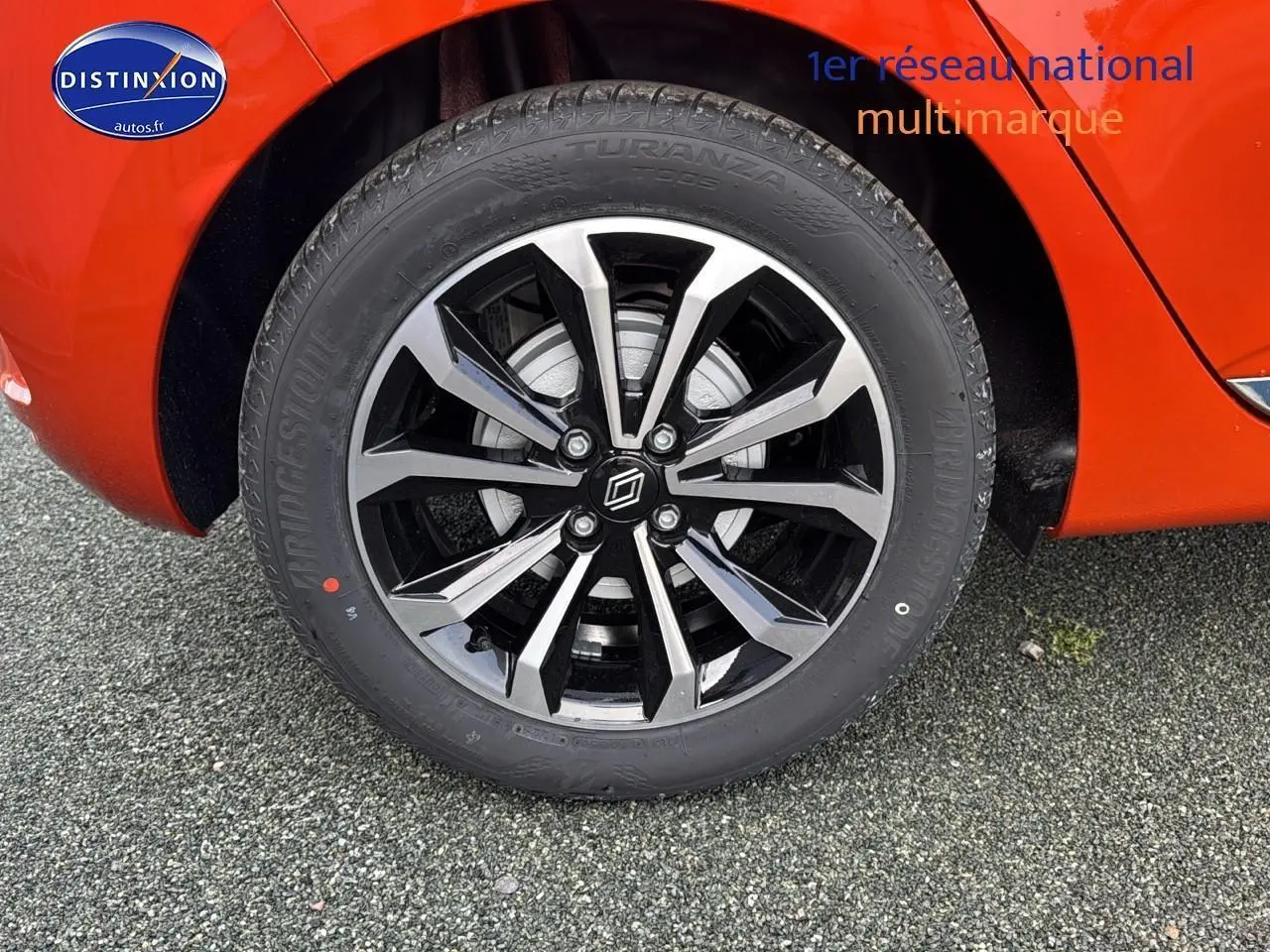 Gros plan sur la jante alu noire et argent de la Renault Clio V orange Valencia, avec pneu Bridgestone Turanza.