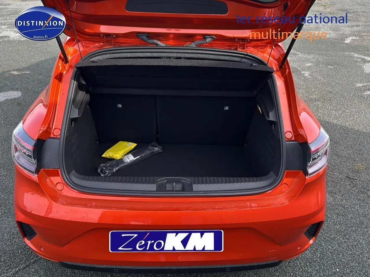 Coffre ouvert vu de l'arrière d'une Renault Clio V 1.6 e-tech 145 techno orange Valencia sur parking.