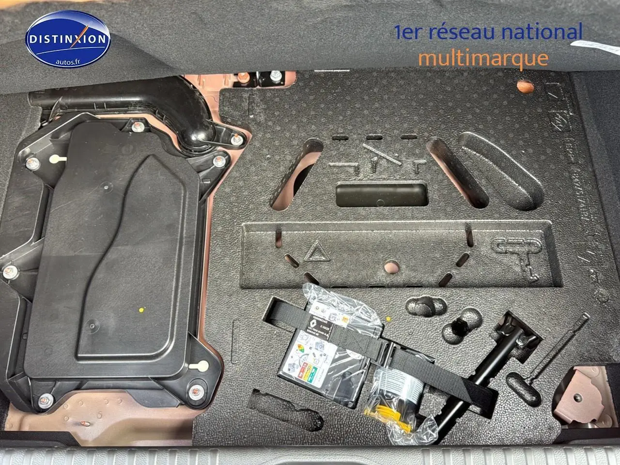 Vue du coffre de la Renault Clio V orange Valencia montrant le rangement sous plancher avec kit de réparation pneus.