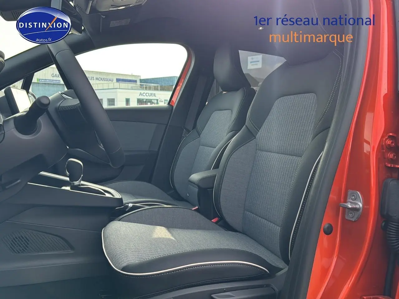 Intérieur avant de la Renault Clio V orange Valencia, vue côté droit sur les sièges sport gris et accoudoir central.