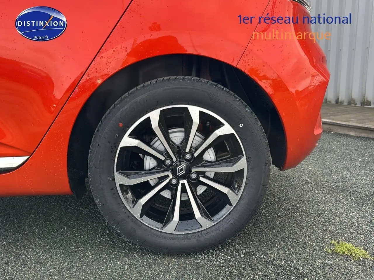 Gros plan sur la roue arrière droite de la Renault Clio V orange Valencia avec jante alliage noire et argentée.