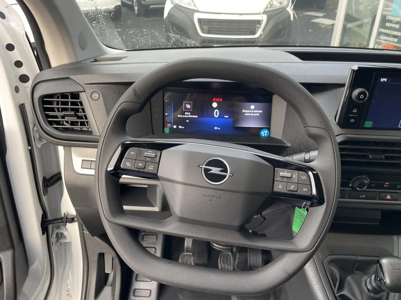 Vue rapprochée du volant noir et du tableau de bord numérique de l'Opel Vivaro blanc 2024 avec boîte manuelle.