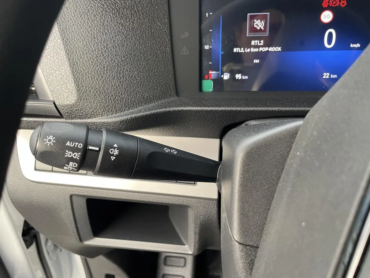 Gros plan sur la manette des feux et clignotants à gauche du volant dans l'habitacle d'un Opel Vivaro blanc 2024.