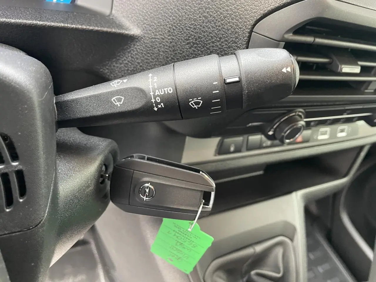 Gros plan intérieur sur la clé Opel insérée à gauche du volant noir avec commandes d'essuie-glace visibles.