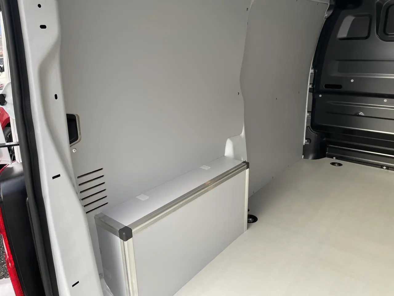 Intérieur arrière du fourgon blanc Opel Vivaro 2024, plancher bois clair et coffrage latéral en bois revêtu.
