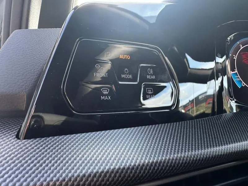 Détail des commandes d'éclairage et désembuage sur le tableau de bord noir d'une Volkswagen Golf gris 2025.