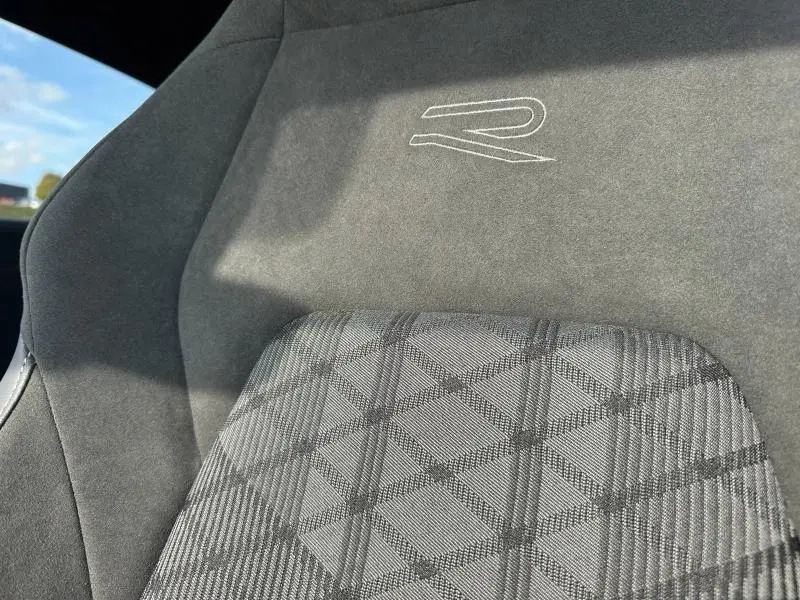 Gros plan sur le siège avant gris de la Volkswagen Golf R-Line Edition 2025 avec logo R brodé et motif à carreaux.