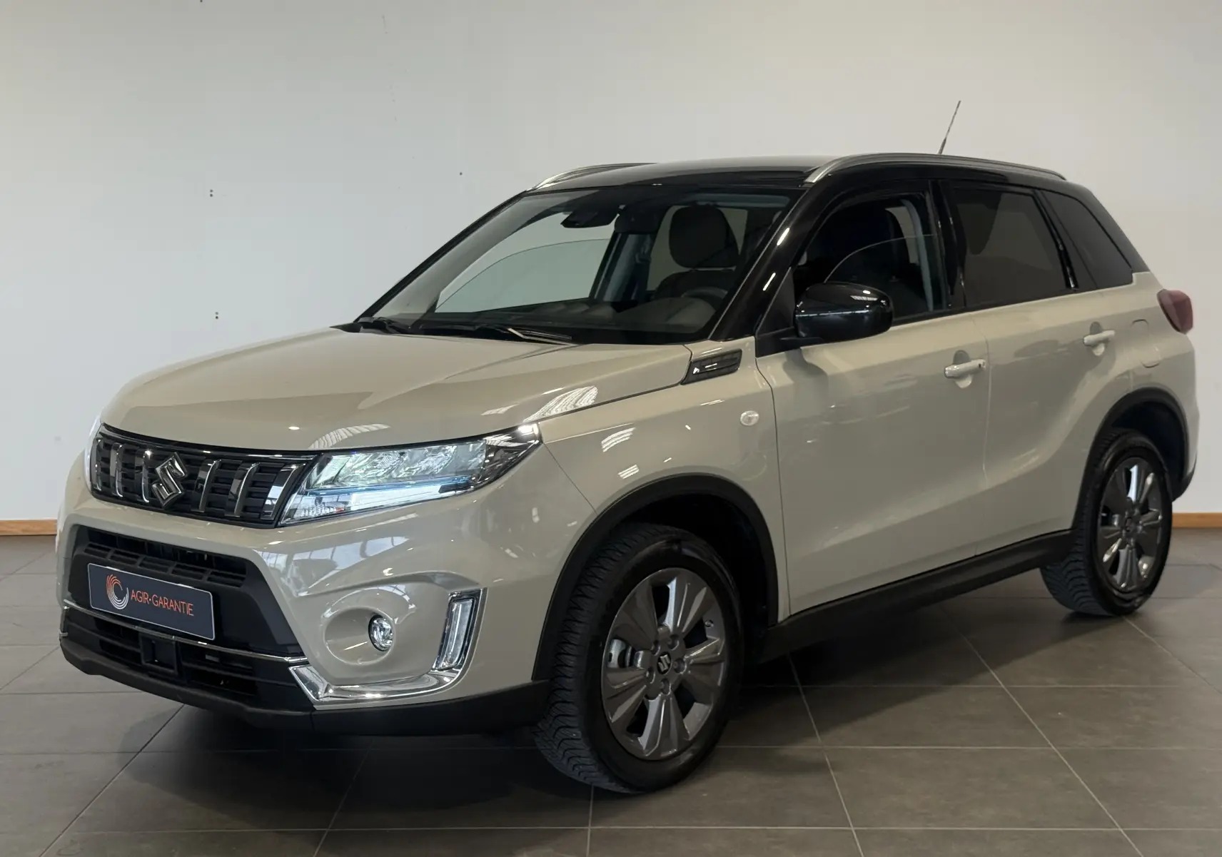 Suzuki Vitara beige 2023 vue 3/4 avant droit avec toit noir et jantes alliage foncé.
