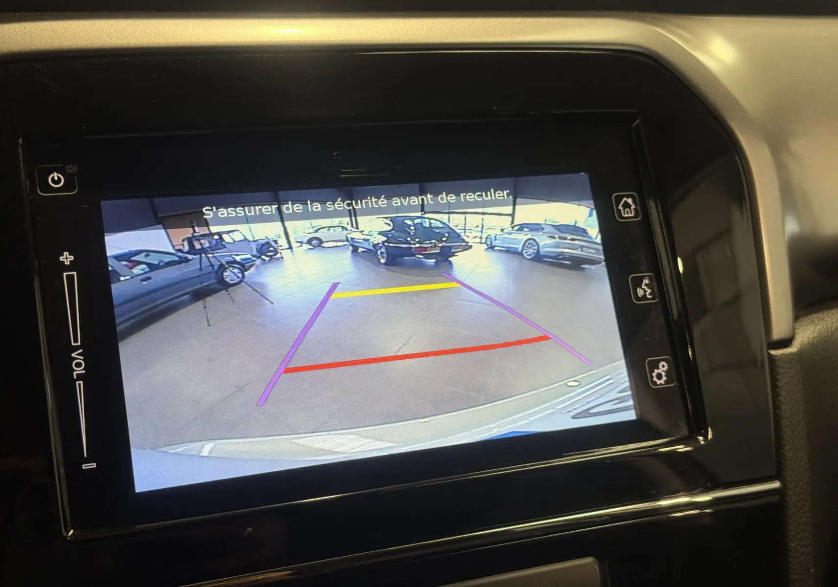 Écran de caméra de recul du Suzuki Vitara beige 2023, affichant les lignes d'aide au stationnement en intérieur.