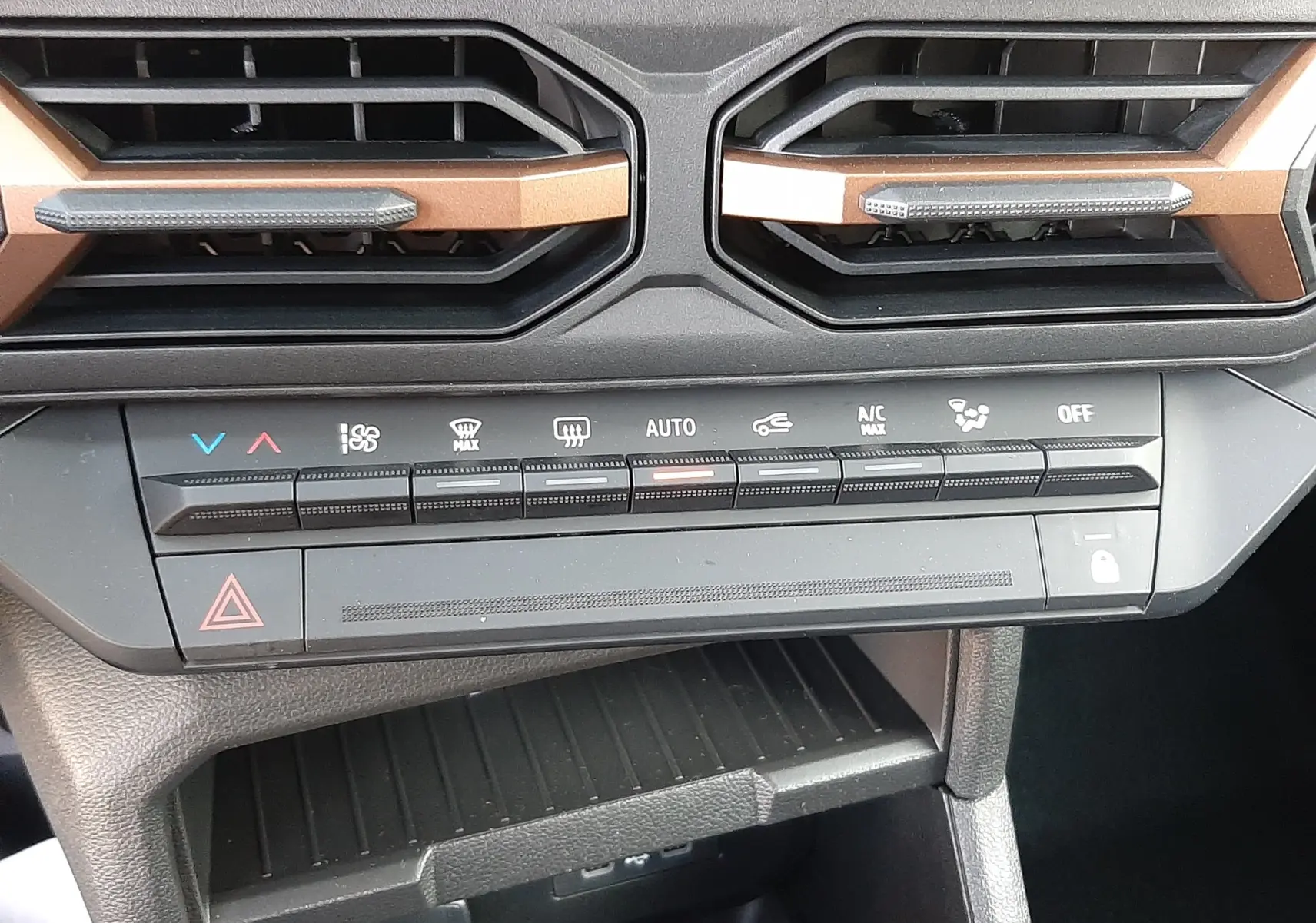 Gros plan sur la console centrale du Dacia Duster 2025, mettant en valeur les aérateurs sable et les commandes climatisation.