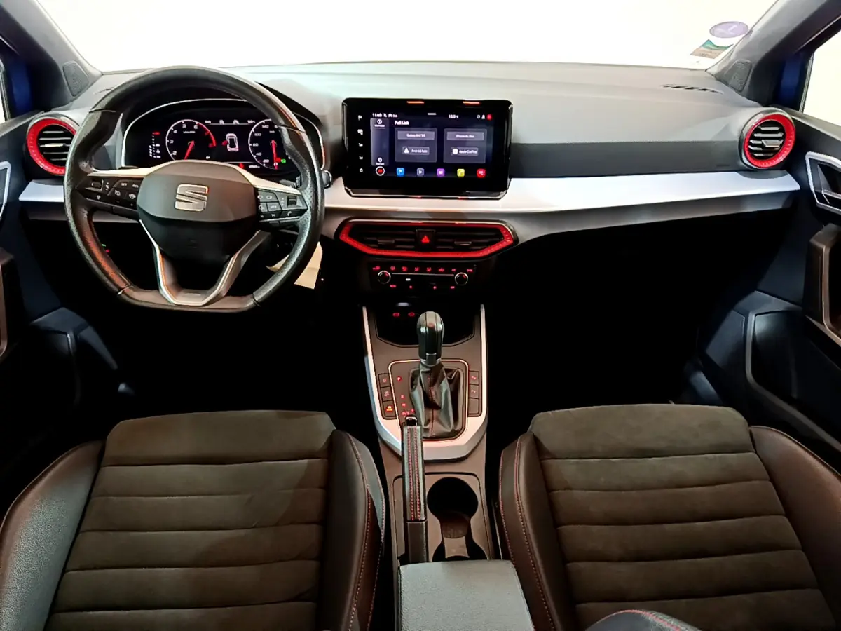 Intérieur du SEAT Arona bleu 2022, vue de face sur le tableau de bord avec écran tactile et détails rouges autour des aérateurs.