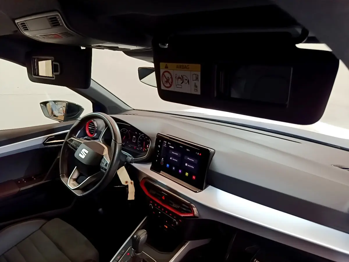 Intérieur du SEAT Arona 2022 côté conducteur, tableau de bord moderne avec écran tactile et accents rouges.
