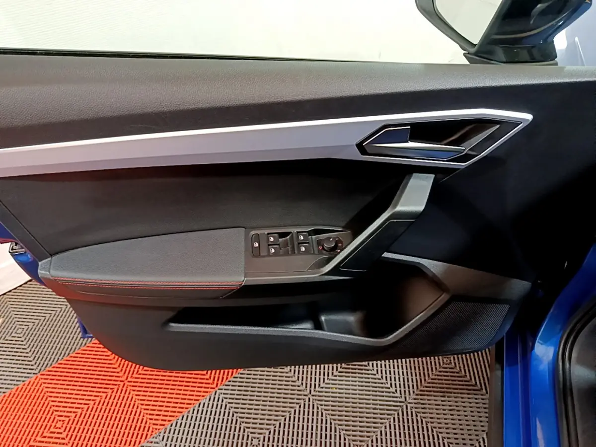 Vue rapprochée de la porte avant gauche bleu du SEAT Arona 2022 avec commandes électriques et poignée argentée.