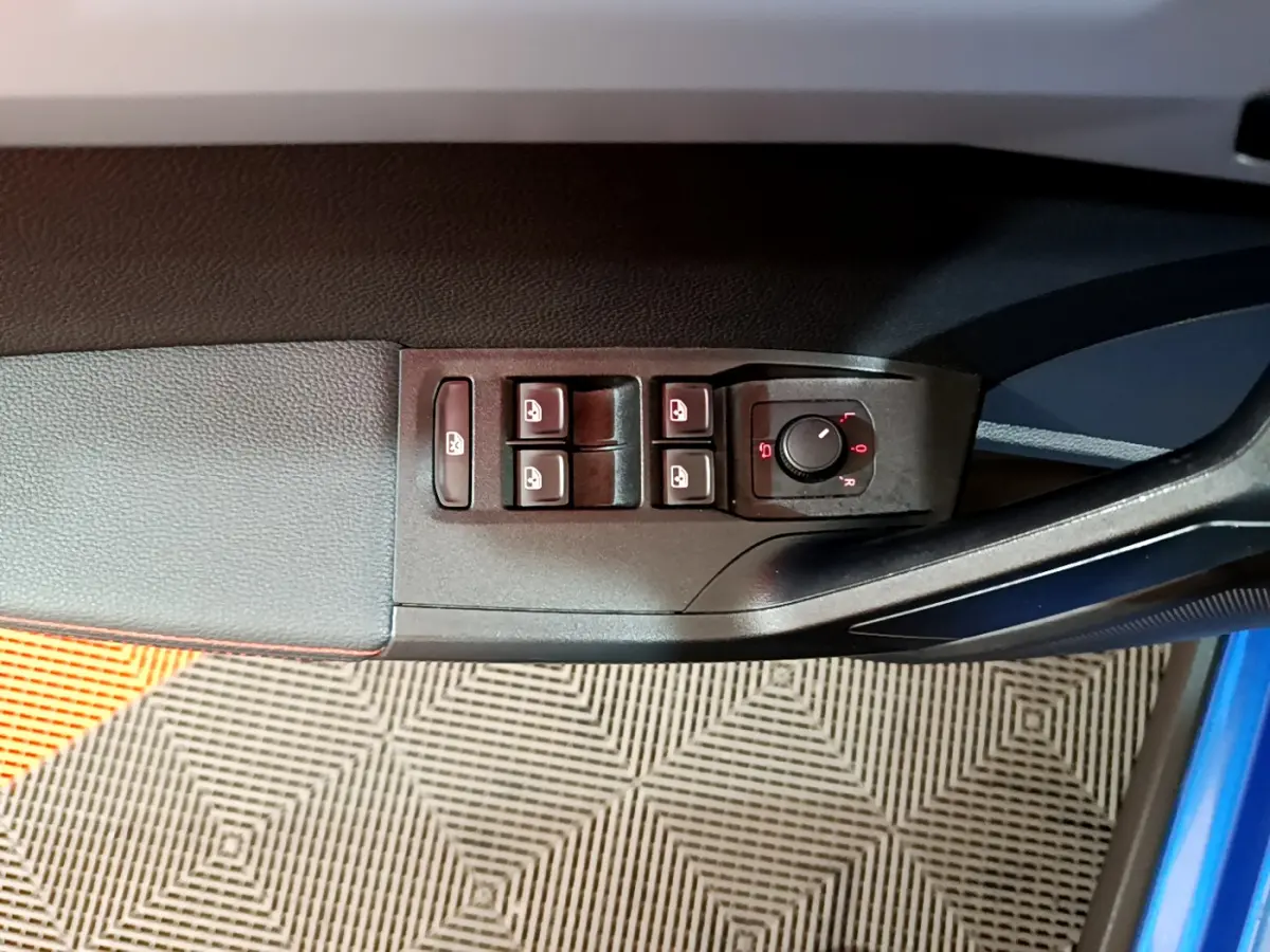 Vue rapprochée des commandes de lève-vitres et rétroviseurs sur la portière côté conducteur d'une SEAT Arona bleu 2022.