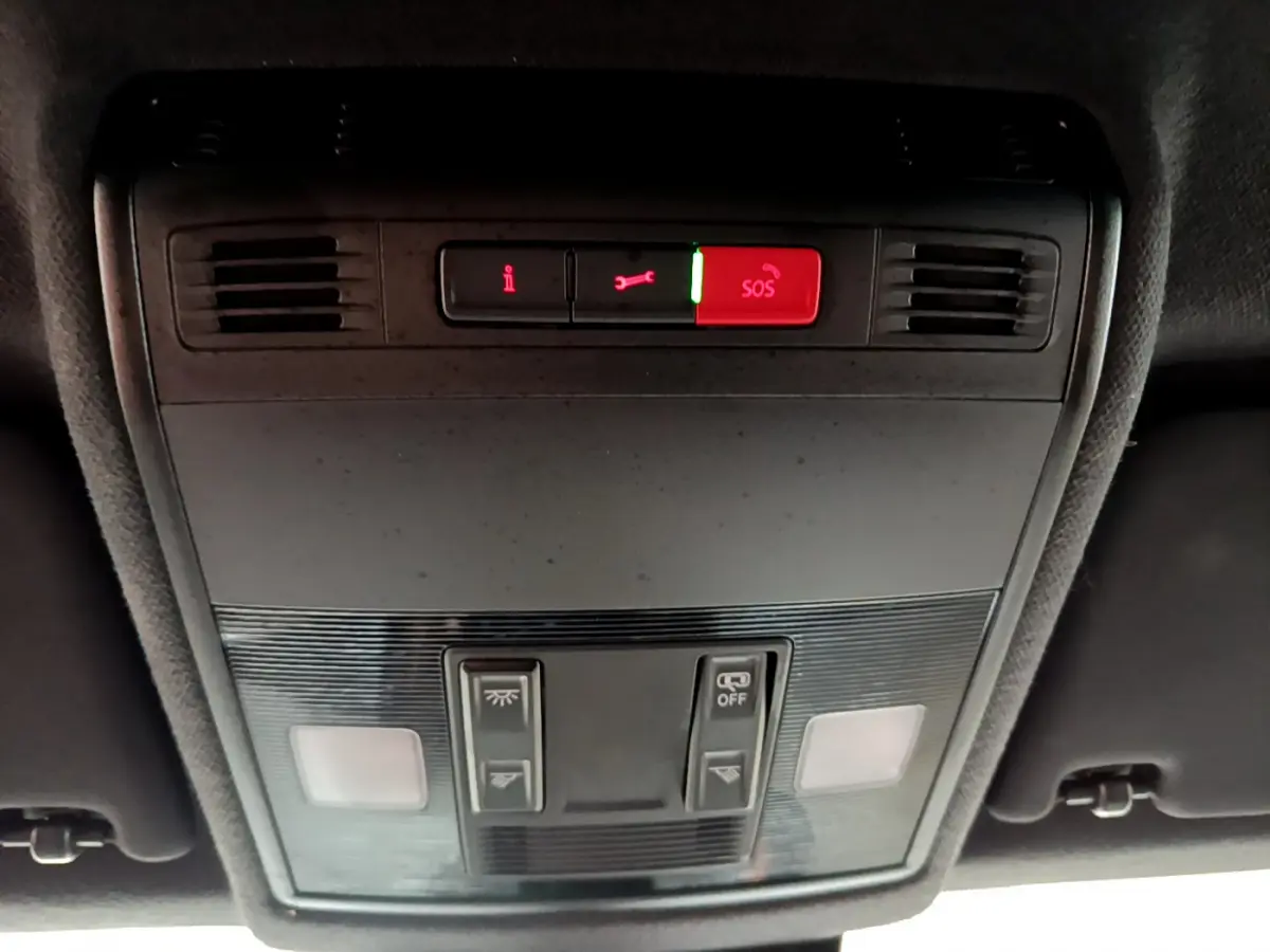 Vue en plongée du panneau de commandes de toit intérieur du SEAT Arona bleu, avec bouton SOS rouge allumé.
