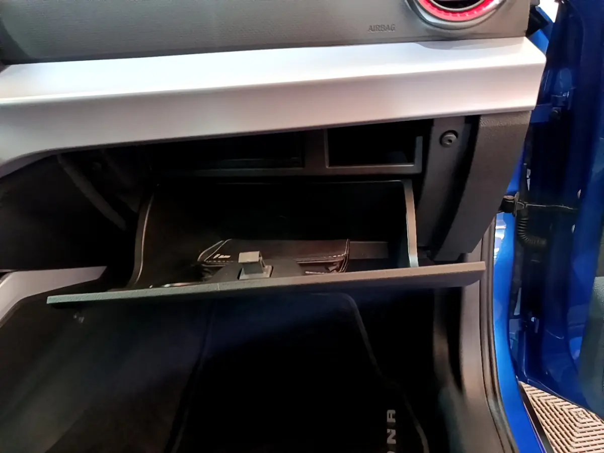 Vue rapprochée de la boîte à gants ouverte côté passager d'une SEAT Arona bleu 2022 avec tableau de bord gris clair.