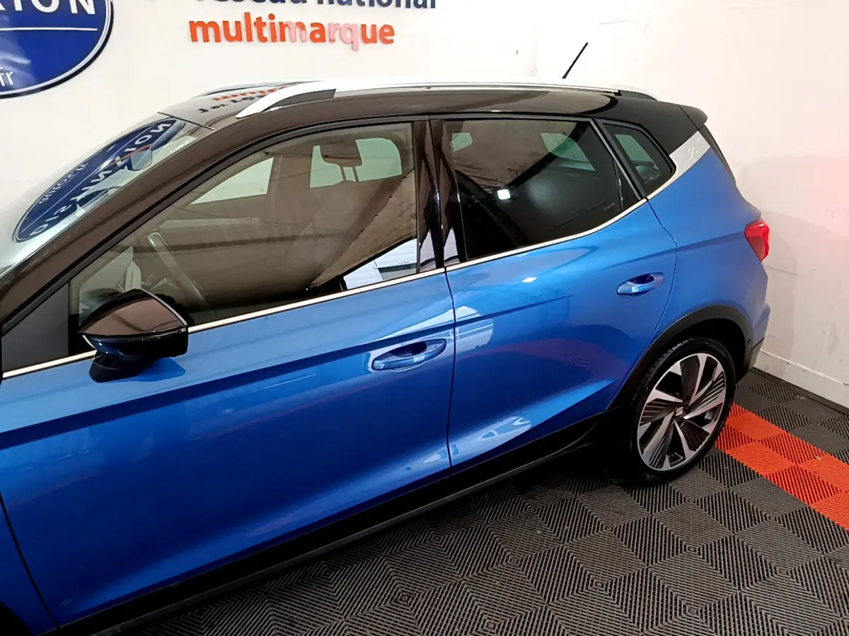 Vue de profil côté gauche du SEAT Arona bleu 2022 avec toit noir et jantes alliage distinctives.