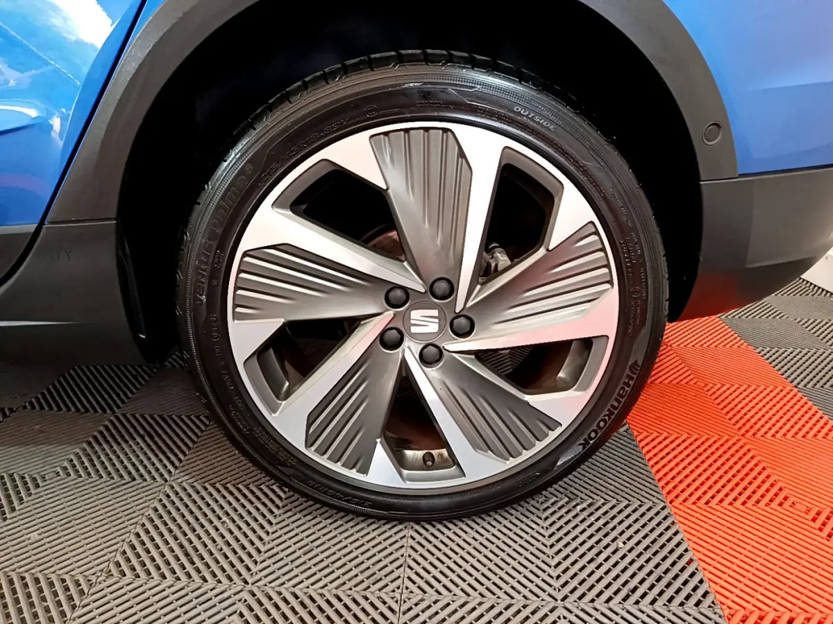 Gros plan sur la roue avant droite d'un SEAT Arona bleu 2022 avec jante alliage au design moderne.
