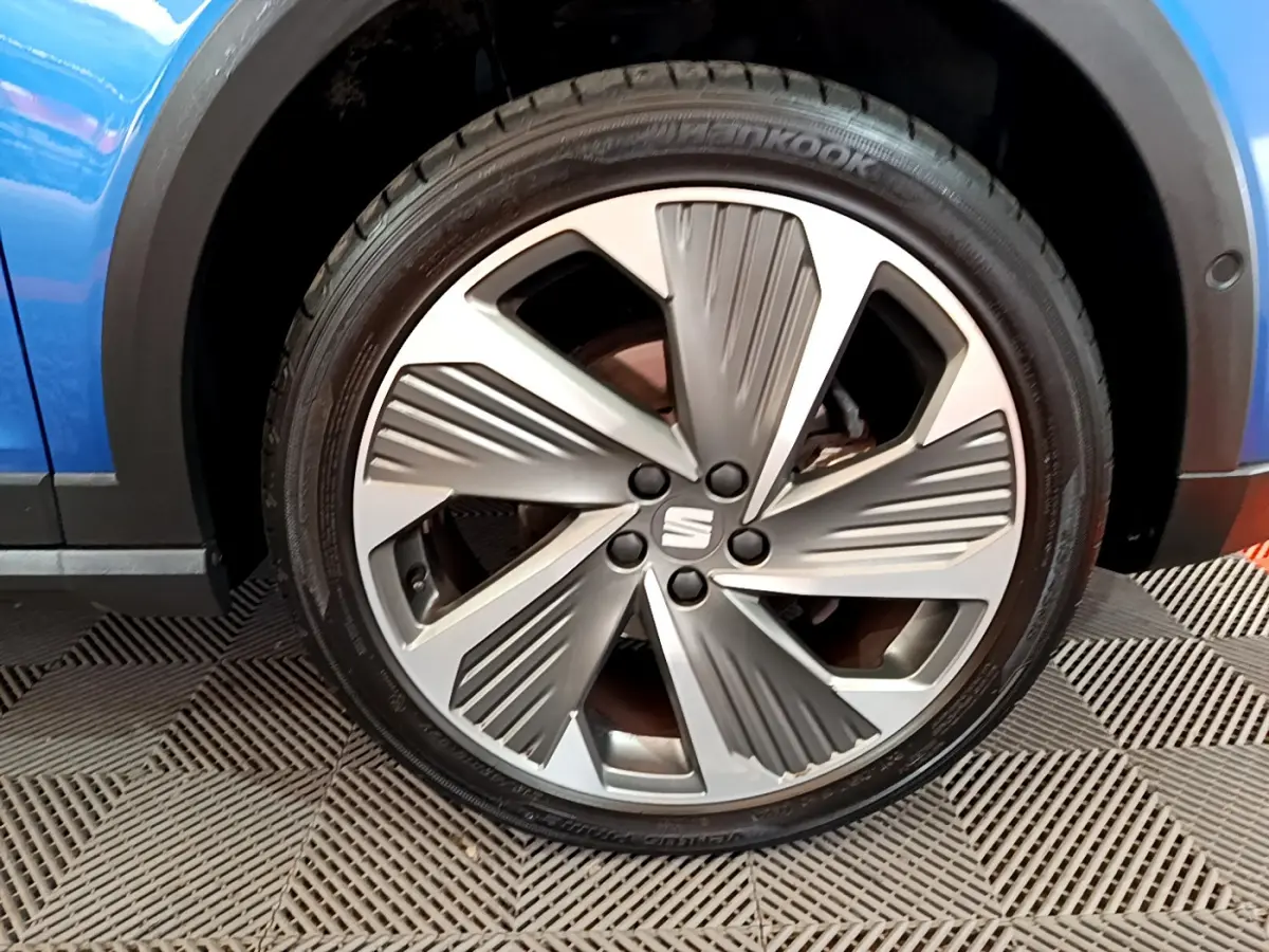 Gros plan sur la jante alu argentée du côté avant gauche d'une SEAT Arona bleue 2022, avec logo central visible.