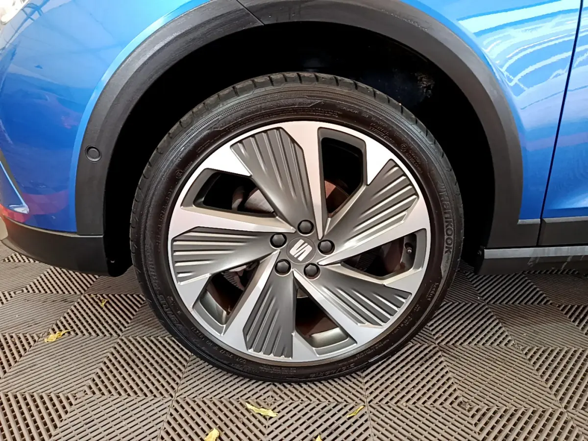 Gros plan sur la roue avant droite du SEAT Arona bleu 2022, mettant en valeur la jante alu au design moderne.