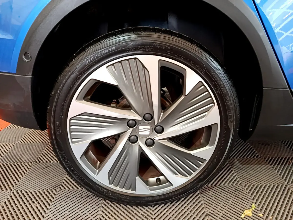 Gros plan sur la roue avant droite d'une SEAT Arona bleu 2022 avec jante alliage au design moderne.