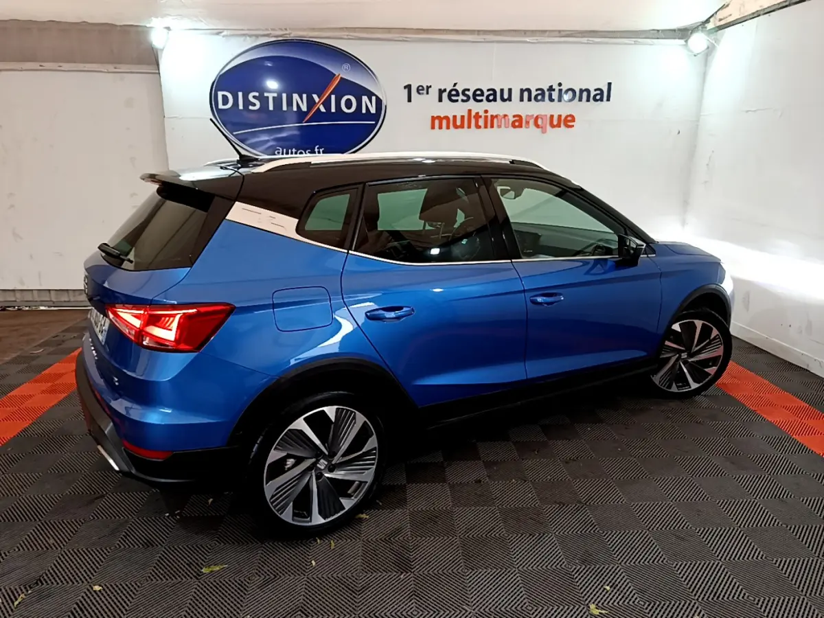 SEAT Arona bleu 2022 en vue 3/4 arrière droit, toit noir et jantes alliage distinctives dans showroom