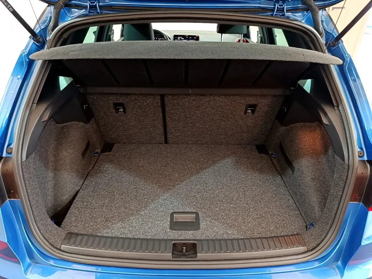 Coffre ouvert vu de l'arrière d'un SEAT Arona bleu 2022, montrant l'espace de chargement et la tablette de séparation.