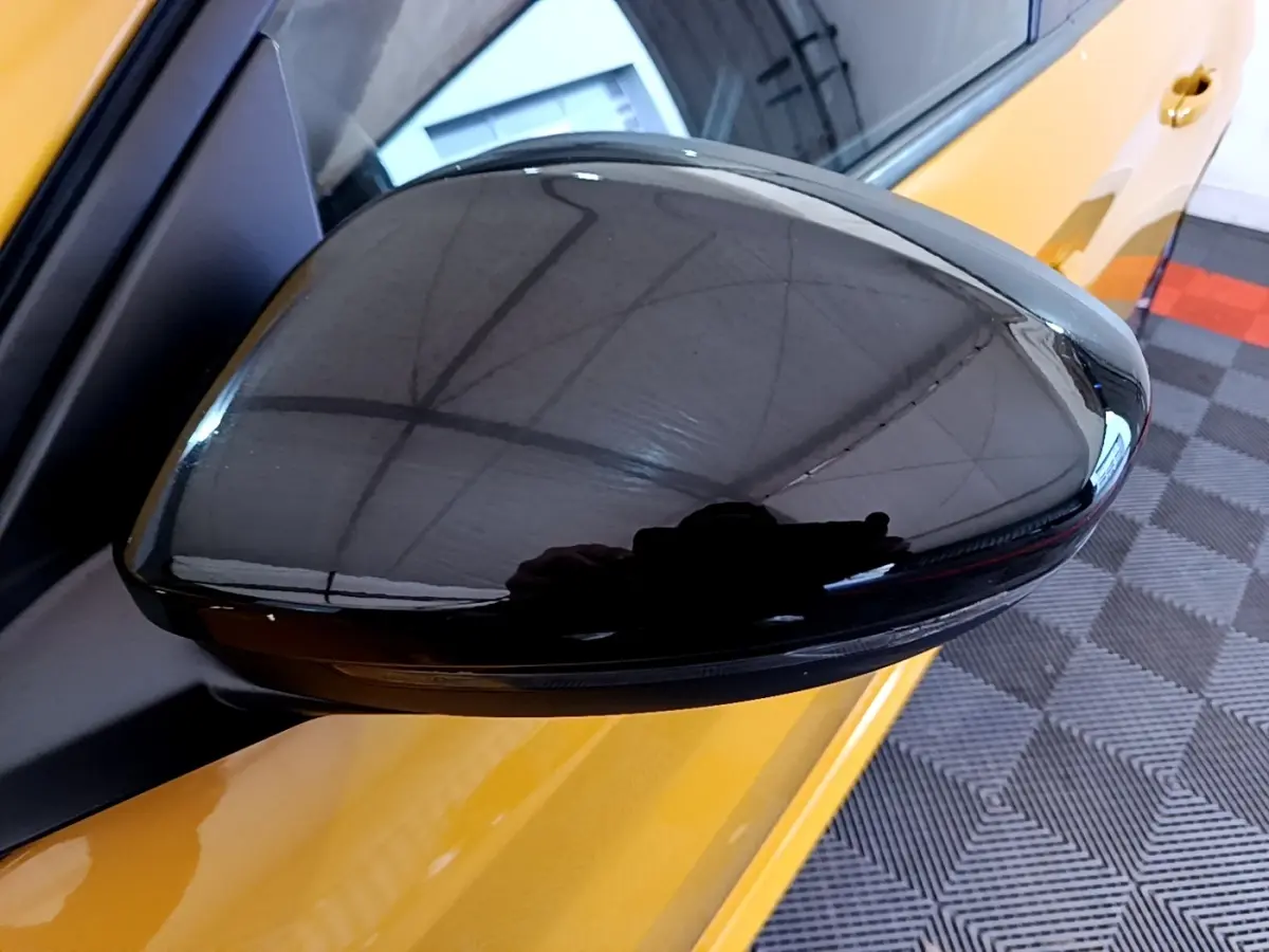Rétroviseur noir en gros plan côté gauche d'une Peugeot 208 jaune PureTech 100 S&S EAT8 Allure Pack 2023.