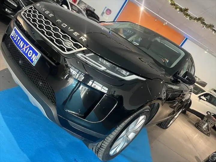 Vue 3/4 avant d'un Range Rover Evoque noir Santorini avec calandre distinctive et phares LED dans un showroom.