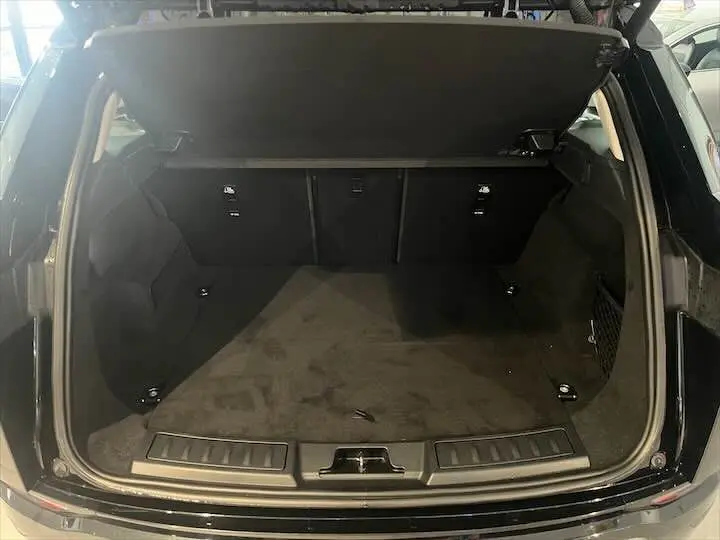Coffre ouvert du Range Rover Evoque noir Santorini, vue arrière montrant l'espace de chargement et la moquette noire.