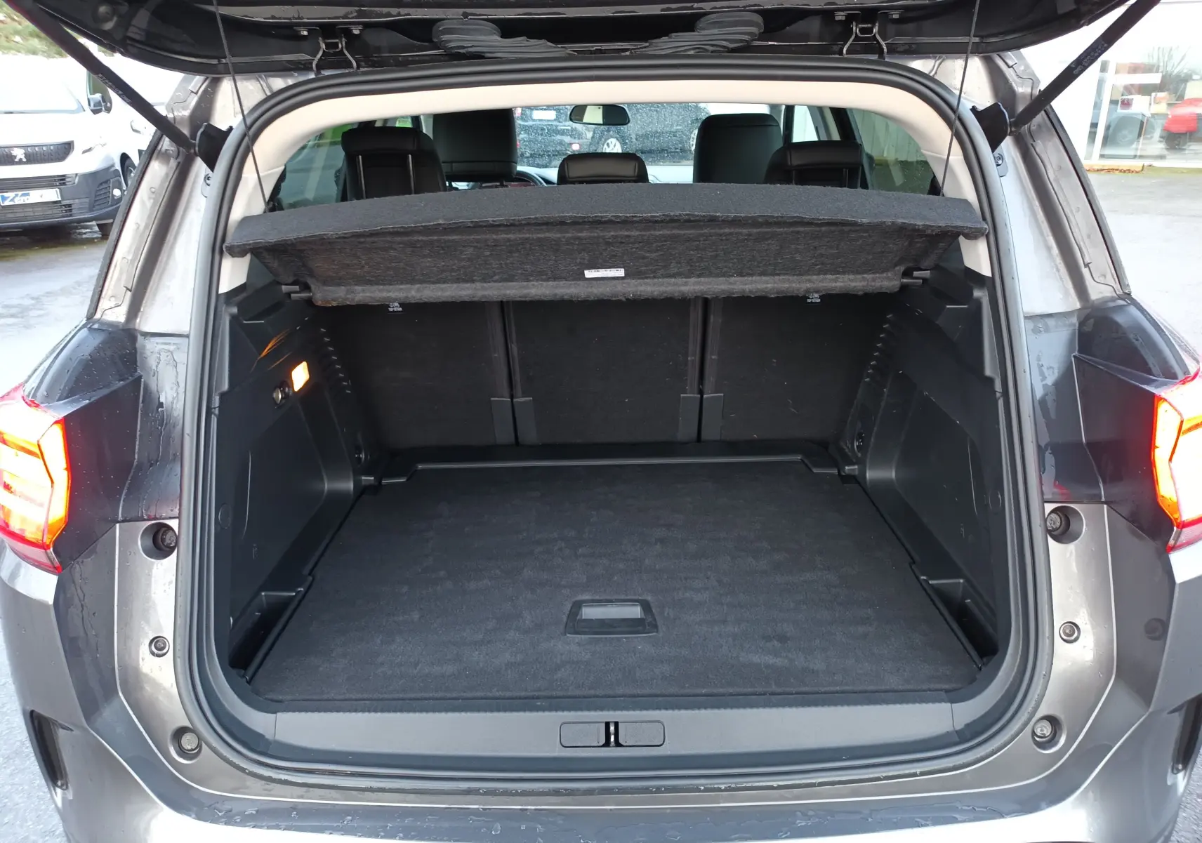 Coffre ouvert vu de l'arrière du Citroën C5 Aircross gris platinium, montrant un espace de chargement vide et propre.