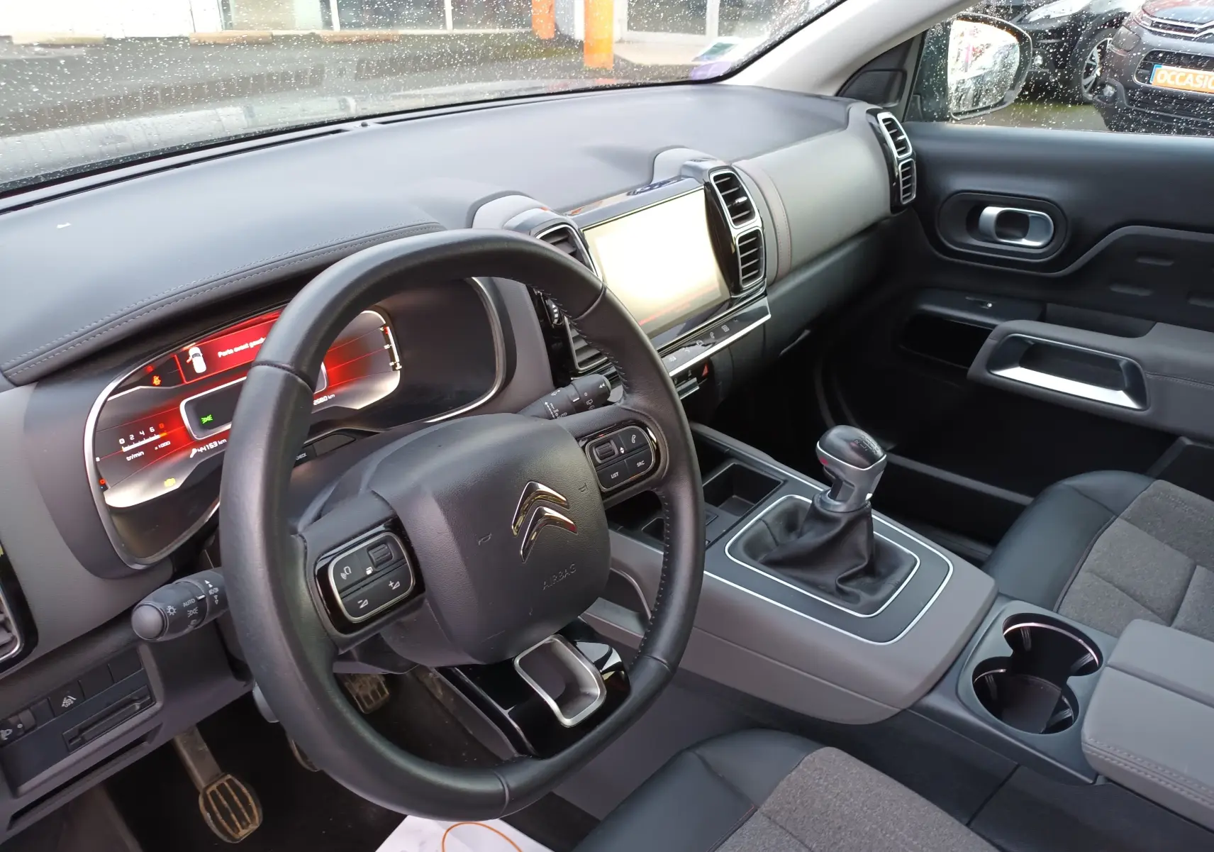 Intérieur du Citroën C5 Aircross gris platinium, vue côté conducteur sur le tableau de bord et levier de vitesses manuel.