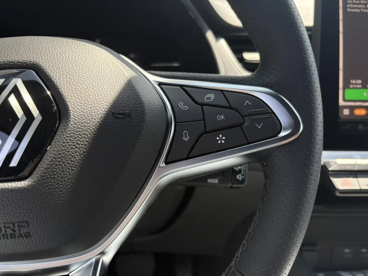 Gros plan sur le volant cuir multifonctions du Renault Captur noir étoile, avec commandes intégrées et logo central.