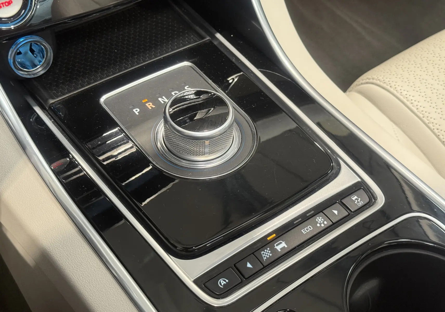 Vue rapprochée de la console centrale noire avec sélecteur rotatif de boîte auto sur Jaguar XE beige 2015.