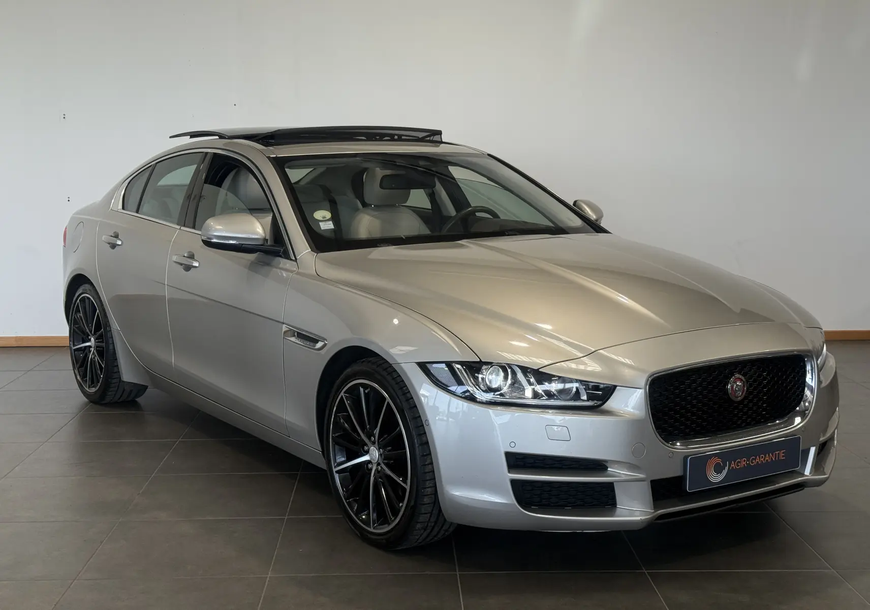 Jaguar XE 20d 180 ch Prestige beige vue 3/4 avant droit avec toit ouvrant et jantes noires élégantes