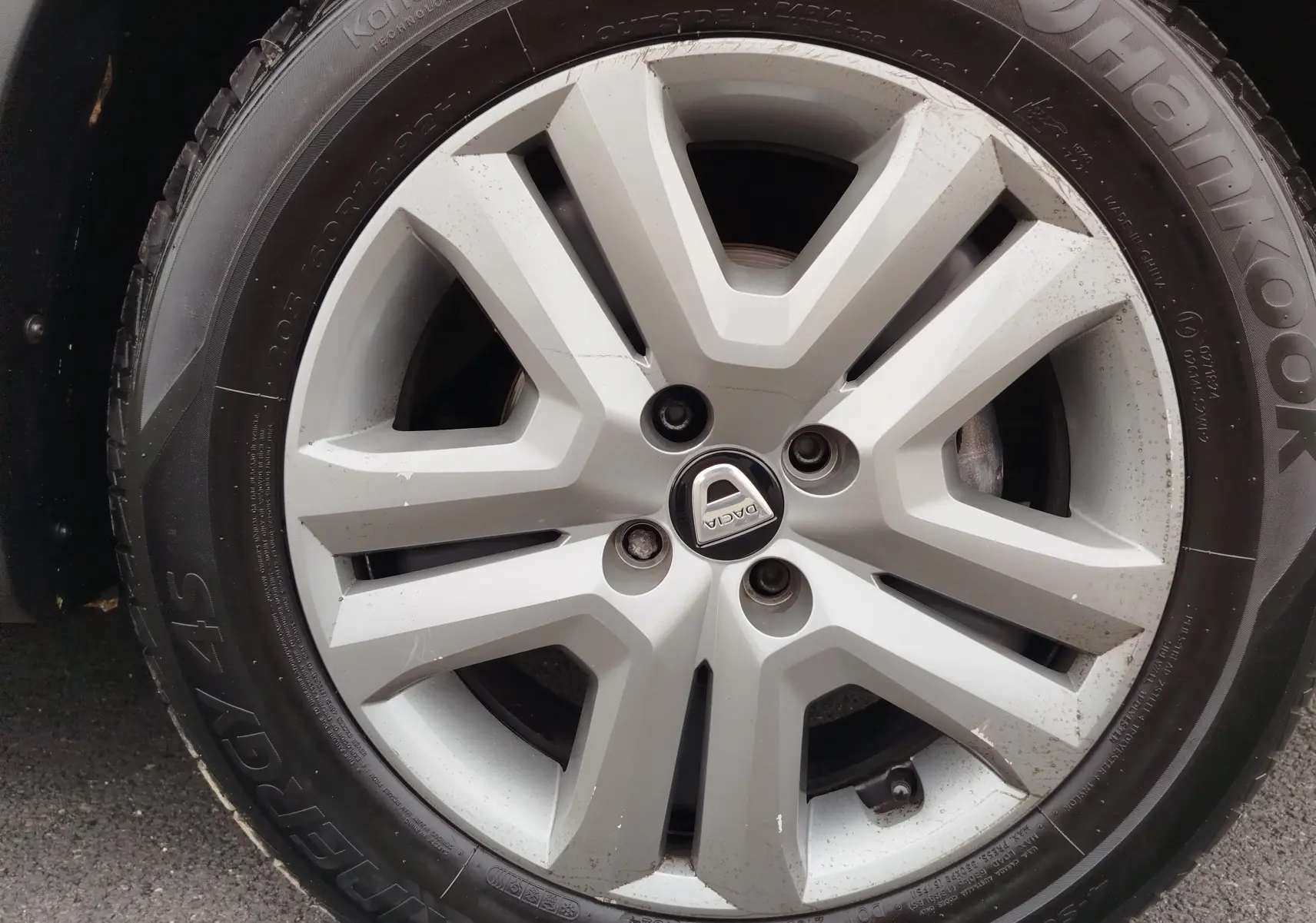 Gros plan sur la jante alliage argentée avec logo Dacia d'une Sandero Stepway blanc glacier de 2021.