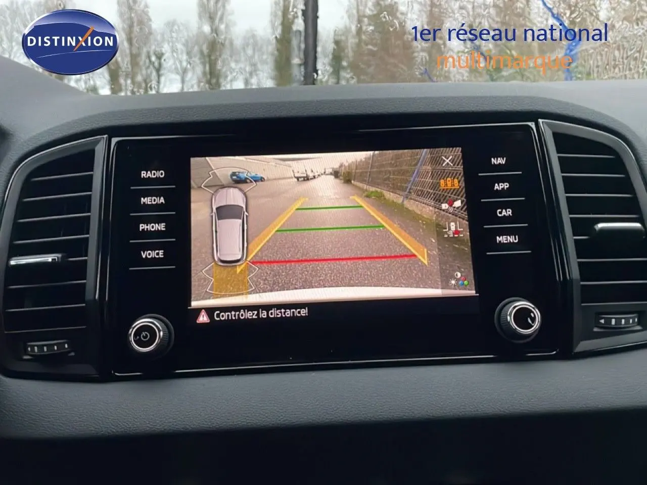 Écran central du Skoda Karoq gris argent 2025 affichant la caméra de recul avec lignes de guidage colorées.