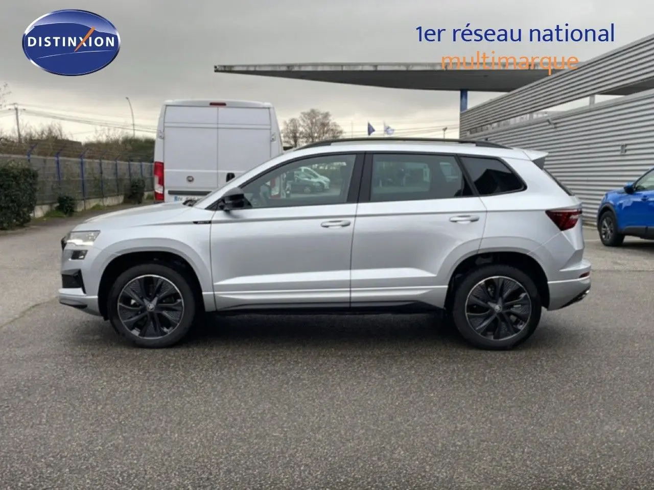 Vue de profil côté gauche d'un Skoda Karoq gris argent métal 2025 avec jantes noires et toit blanc.