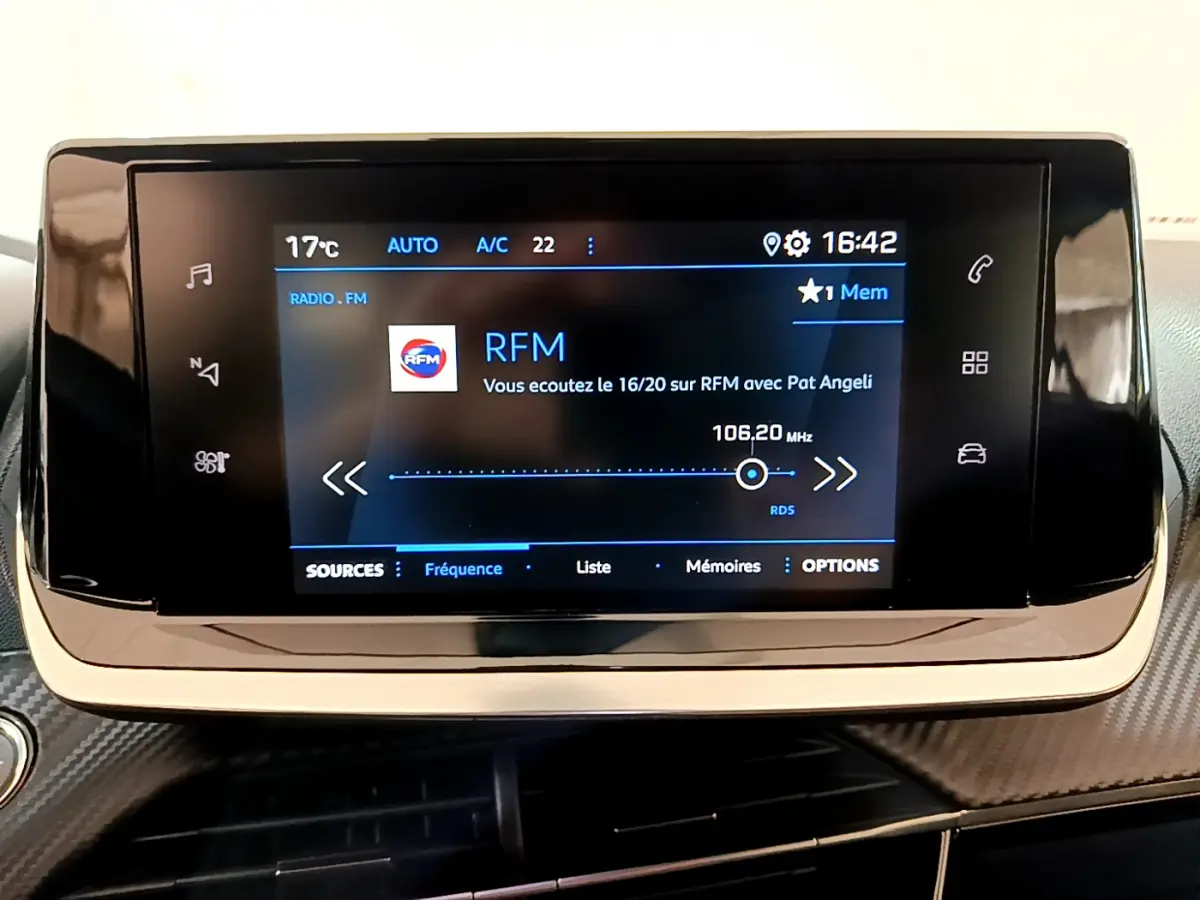 Écran tactile central de la Peugeot 2008 2022 affichant la radio RFM avec commandes tactiles sur fond noir brillant.