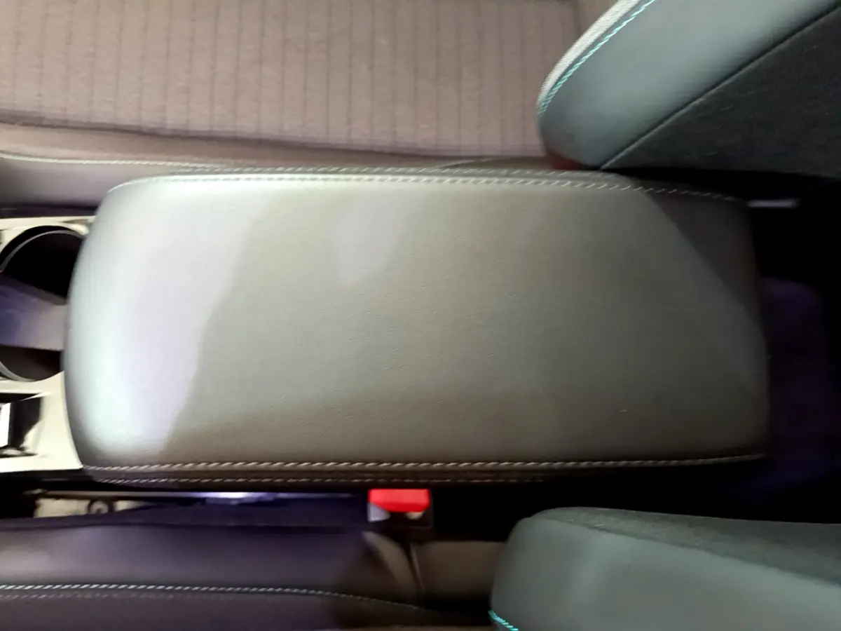 Vue rapprochée de l'accoudoir central en cuir gris foncé à surpiqûres blanches dans l'habitacle d'une Peugeot 2008.