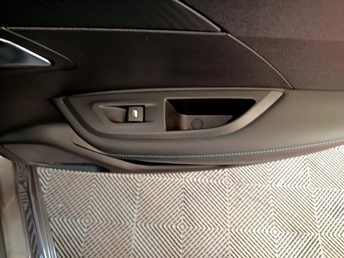 Gros plan sur la poignée intérieure et le bouton de lève-vitre côté gauche d’une Peugeot 2008 gris foncé, version 2022.