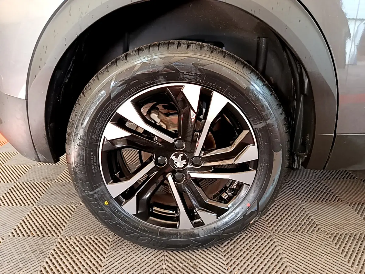 Gros plan sur la roue avant gauche d’un Peugeot 2008 gris foncé, avec jante alliage noire et argentée au design moderne.